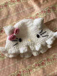 a crocheted hello kitty hat laying on top of a bed