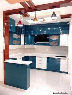 a kitchen with blue cabinets and white counter tops, lights hanging from the ceiling over the island