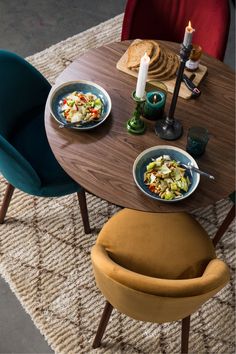 the table is set with two plates of food on it and there are candles in the background