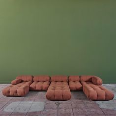 a brown couch sitting on top of a tiled floor next to a green painted wall