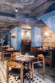 an empty restaurant with blue walls and wooden tables set up for two people to eat