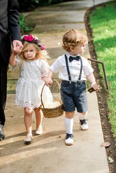 two young children walking down a sidewalk with an adult holding the hand of another child