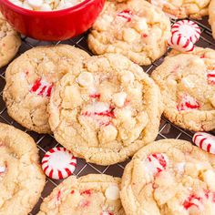 cookies with candy canes and marshmallows are on a cooling rack next to a red bowl