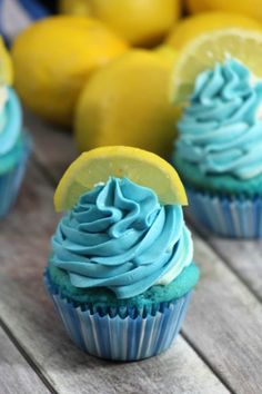 three cupcakes with blue frosting and lemon slices