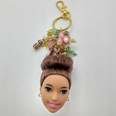 a doll head with a keychain attached to it's back and some beads on top