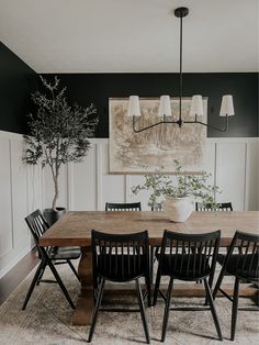 a dining room table with black chairs and a painting on the wall in the background