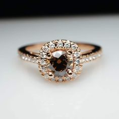 an engagement ring with a brown diamond surrounded by white and gold diamonds on a table