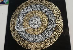 an intricately decorated black and gold plate with arabic calligraphy on the front cover