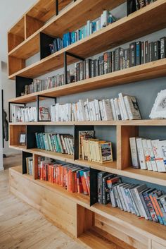 a bookshelf filled with lots of books on top of wooden shelves