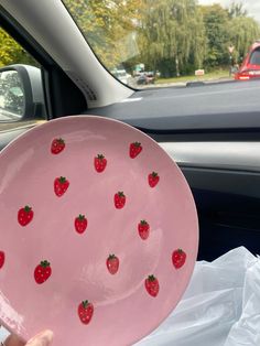 a pink plate with strawberries painted on it in the front seat of a car