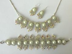 a white necklace and earring set with pearls on the bottom, along with other jewelry pieces