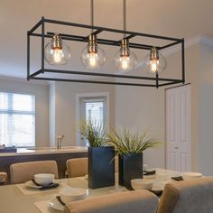 a dining room table and chairs with lights hanging over it