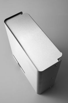 an empty silver box sitting on top of a white table next to a gray wall