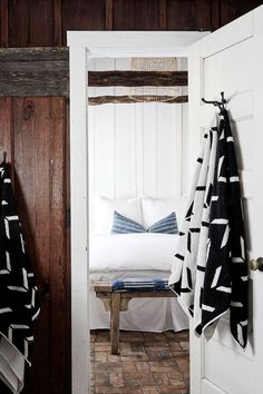 an open door leading to a bedroom with a white bed and black and white throw