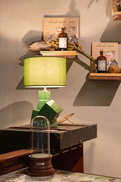 a table with a lamp and some books on it next to a wall mounted shelf