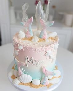 there is a cake decorated with sea shells and mermaid tails on the top of it