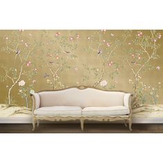 a white couch sitting in front of a wall covered in flowers and birds on it