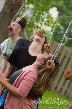 people eating donuts hanging from strings in the air