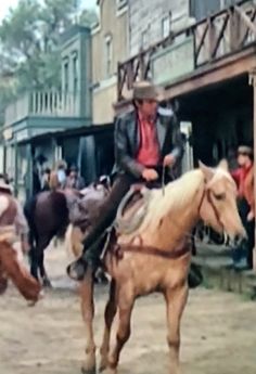 a man riding on the back of a brown horse next to other men in cowboy hats