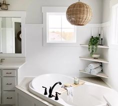 a bathroom with a large white bathtub next to a sink and window in it