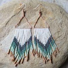 two pairs of beaded earrings sitting on top of a rock