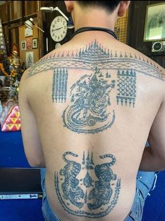 the back of a man with tattoos on his upper and lower part of his body