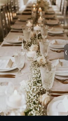 a long table is set with white flowers and candles for a formal dinner or party