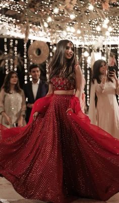 a woman in a red dress is dancing on the dance floor with other people around her