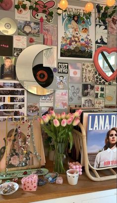 there is a wall with many pictures and flowers on the table in front of it