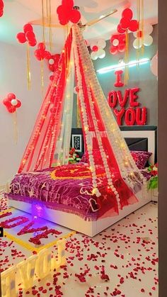 a bed decorated with red and white decorations in a room that has balloons floating from the ceiling