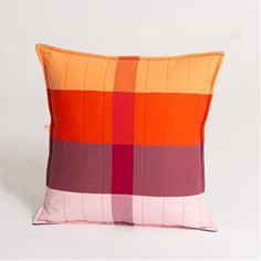 an orange and pink pillow sitting on top of a white floor