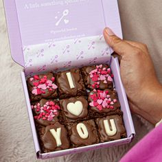 a person holding a box of chocolates that say i love you