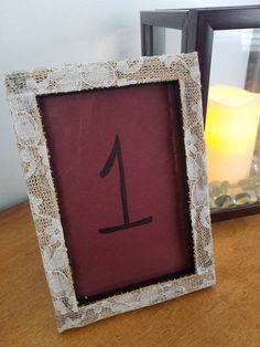 a wooden table topped with a framed photo next to a candle