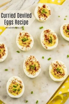 deviled eggs with chives and seasoning on a white marble countertop next to yellow napkin