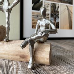 a silver figurine sitting on top of a piece of wood