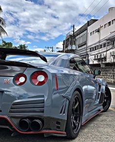 the rear end of a gray sports car parked in a parking lot next to other cars