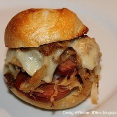 a sandwich with meat, cheese and onions on a white plate sitting on a table