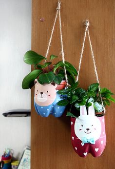 two planters with plants in them hanging on a doorknock, one is shaped like a rabbit and the other has a bunny face