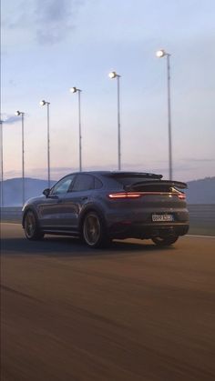 a porsche cayen is driving down the road at night with street lights in the background