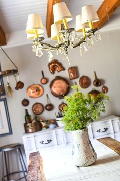 a table with a vase on it and some lights hanging from the ceiling over it