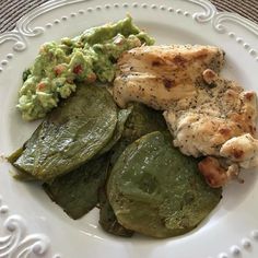 a white plate topped with chicken, green beans and guacamole