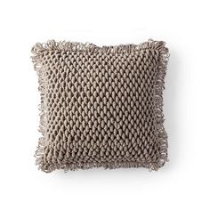 a gray pillow with braiding on the front and back, sitting on a white surface