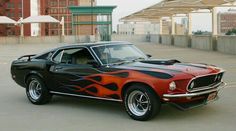 an orange and black car with flames painted on it's hood parked in a parking lot