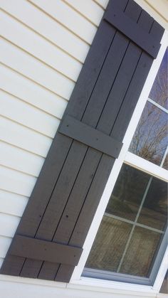 an open window on the side of a house with black shutters and white trim