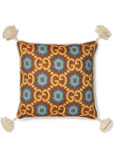 an orange and blue pillow with tassels on it