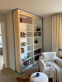 a living room filled with furniture and bookshelves next to a window covered in curtains