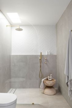 a bathroom with a toilet, sink and shower head in the corner next to it