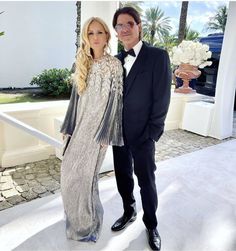 a man in a tuxedo standing next to a woman wearing a dress and tie