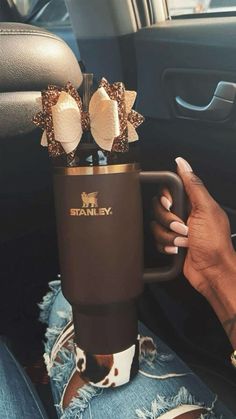 a woman is holding a coffee cup in her car