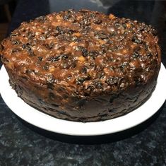 a chocolate cake sitting on top of a white plate next to a black countertop